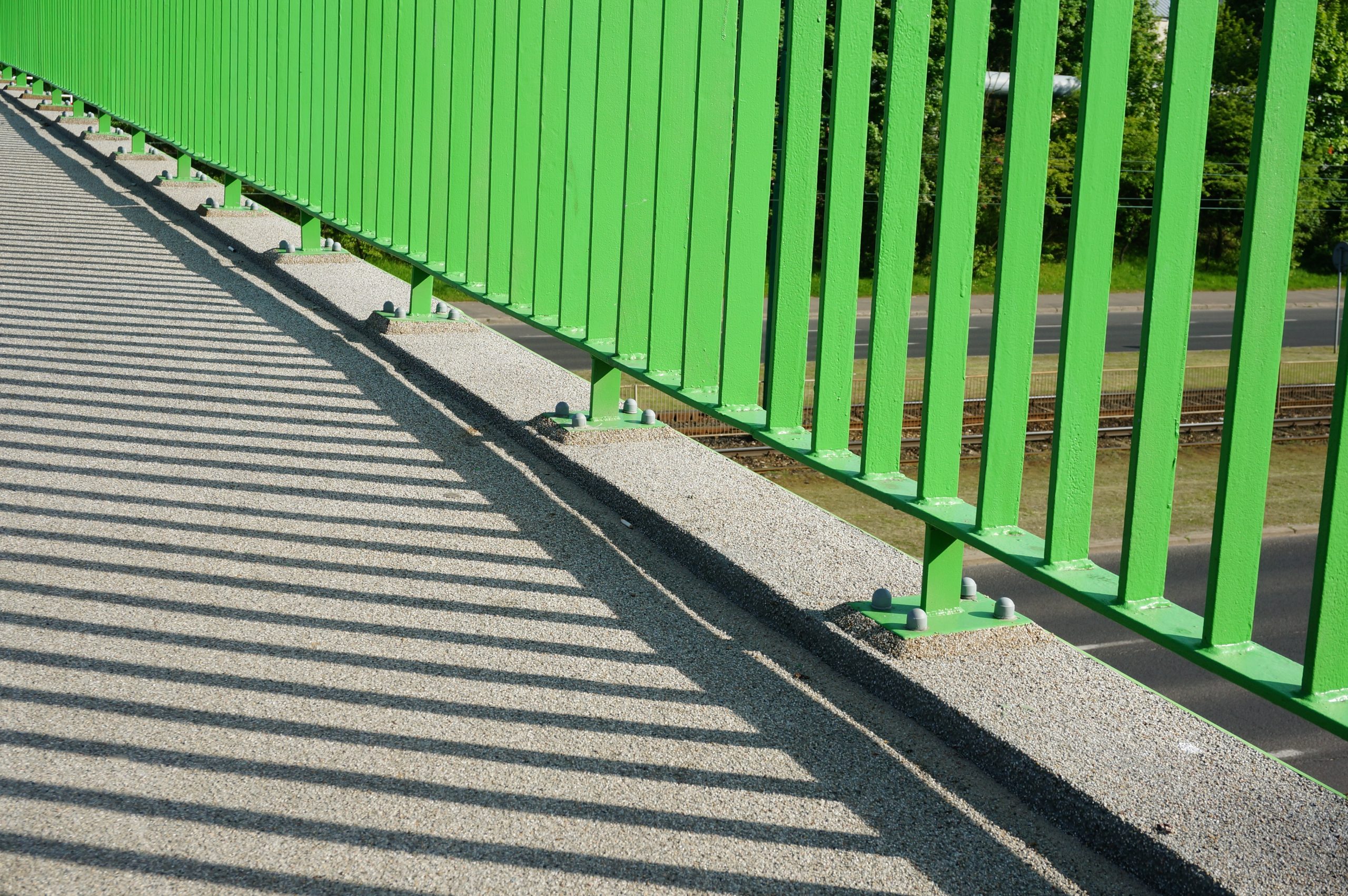 A closeup of the base of the green barrier of an overpass bridge